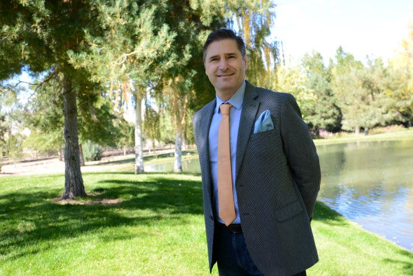 Pasquale Iovinella smiling at the camera wearing a necktie and pocket square