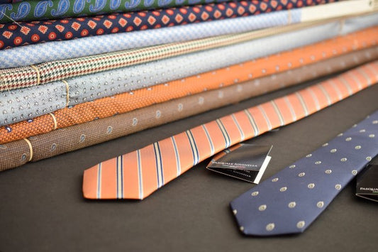 Two neckties on a table with bolts of fabric in the background