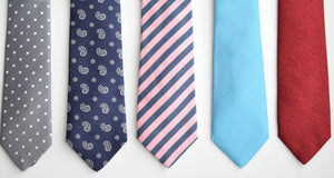 Five neckties laying on a table displaying the five designs every man should own