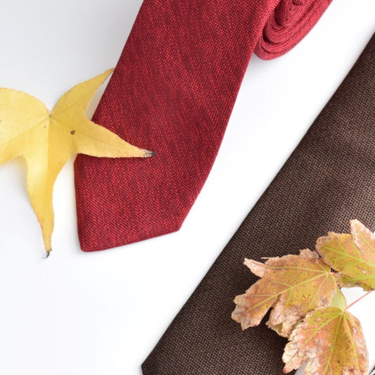 Two neckties on a table with fall leaves
