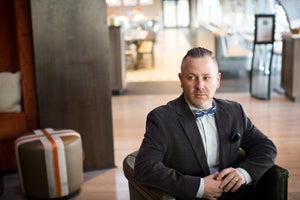 Man sitting looking to the side wearing a bowtie and pocket square